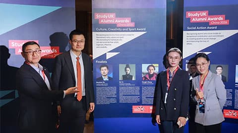 Study UK Awards branding on banners behind them. Winner Shunhao and Virginia standing together at the awards ceremony in China along with other finalists and they are all smiling.
